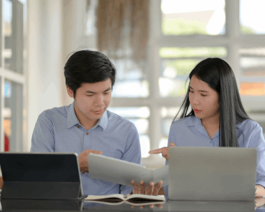 Two linguist compares a bilingual schematic while Chinese Translation Services in New York handles technical terminology.