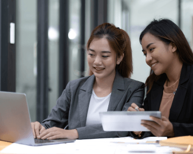 Two editors compare Korean and English pages on screen, using Korean Translation Services in New York for business documents.